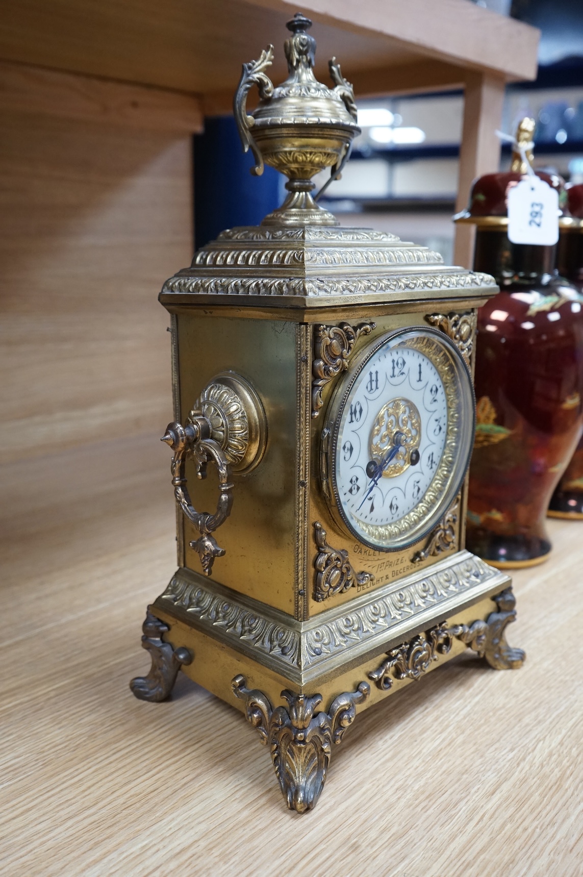 A decorative brass mantel clock with urn surmount, with 1st prize engraved panel, 41cm high